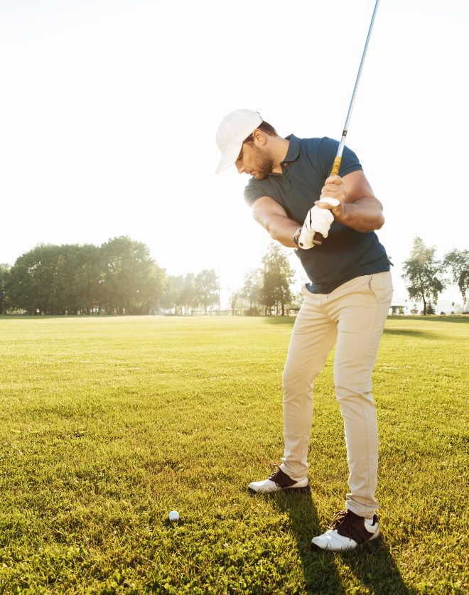 young male golfer hitting ball with club